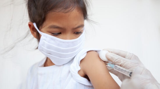Doctor injecting vaccination on asian child girl arm. The child girl wearing protection mask for protect air smog pollution with PM 2.5 and Covid-19 virus. Healthy and medical concept.